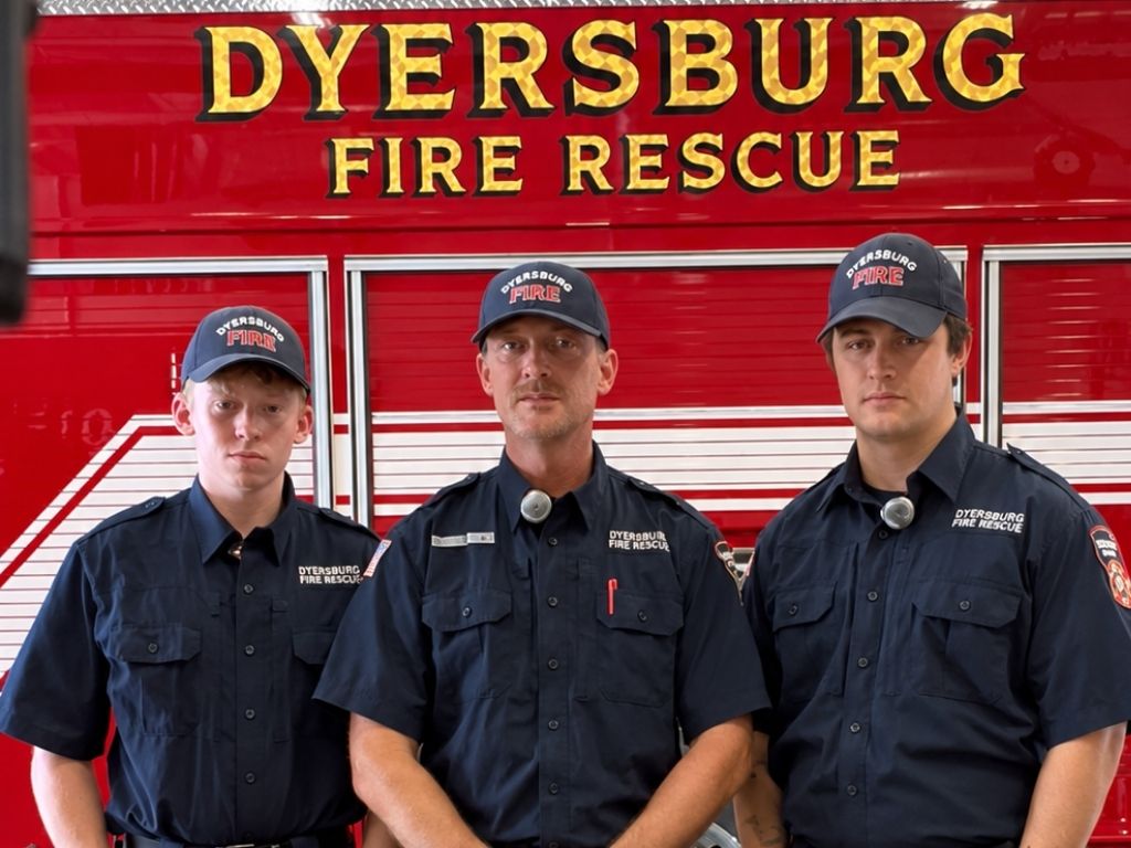 Three firefighters stand in front of a Dyersburg Fire Rescue truck